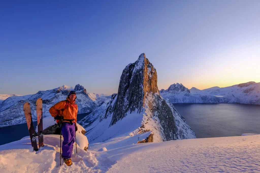 Skitouring man som står på åsen framför det ikoniska Segla-berget, utsikt över havsfjordarna, Fjordgard, Norge