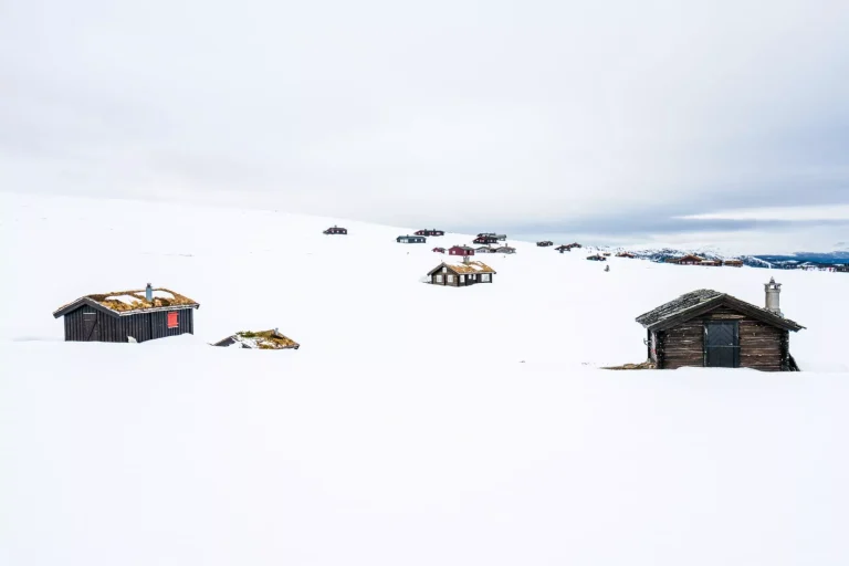 Trästugor utomhus i vackra snötäckta berg och dimmigt landskap i bakgrunden. Arkitektur och säsong koncept. Från Rondane nationalpark i Norge.